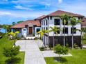 Beautiful two-story home with a terracotta tile roof and manicured front yard with palm trees at 4907 Topsail Dr, Nokomis, FL 34275