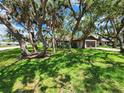 View of the single-story home from the front yard with mature trees providing shade at 5629 Boulder Blvd, Sarasota, FL 34233