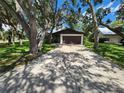 Exterior view of home showing driveway leading to the two-car garage framed by mature trees at 5629 Boulder Blvd, Sarasota, FL 34233