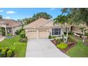 Inviting single-Gathering home featuring a tile roof, two-car garage, and meticulously landscaped front yard with mature trees at 6155 Aviary Ct, Bradenton, FL 34203