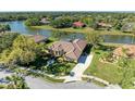 Aerial view of waterfront property with screened pool, tile roof, and lush landscaping on a sunny day at 8315 Eagle Xing, Sarasota, FL 34241