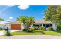 Beautiful single-story home with a wood-paneled garage door, well-maintained lawn, and vibrant foliage at 891 Faulkwood Ct, Sarasota, FL 34232