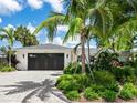 Charming exterior with tropical landscaping and a striking black garage door at 1031 Contento St, Sarasota, FL 34242