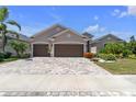Charming single-story home featuring a three-car garage, mature landscaping, and a brick-paved driveway at 12398 Keyridge Loop, Largo, FL 33778