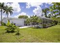 Lush backyard with a screened-in pool area, tropical plants and well-maintained lawn at 3167 Pinetree St, Port Charlotte, FL 33952