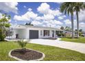 Beautiful home with a well-manicured lawn, driveway, mature trees, and attached garage at 3167 Pinetree St, Port Charlotte, FL 33952