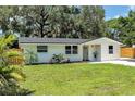 View of a freshly painted single-story home featuring a well-maintained lawn and lovely, mature shade trees at 4041 Linwood St, Sarasota, FL 34232