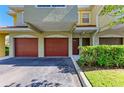 Close up view of townhome garages with brick-red doors and well manicured shrubs at 5001 Baraldi Cir # 22-202, Sarasota, FL 34235