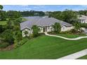 A single-story home with lush landscaping, a well-manicured lawn, and views of a serene lake at 5012 Cherry Laurel Way, Sarasota, FL 34241