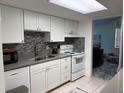 Bright kitchen with white cabinets, stainless steel sink, mosaic backsplash and modern appliances at 5026 Water Oak Dr # 114, Bradenton, FL 34207