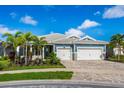 Charming blue home with a three-car garage, brick driveway, manicured lawn, and beautiful landscaping at 5533 Long Shore Loop, Sarasota, FL 34238