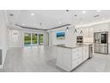 Open-concept living room with tile floors, island kitchen, and sliding glass doors to the pool area at 5533 Long Shore Loop, Sarasota, FL 34238