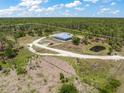 Aerial view of a property surrounded by lush greenery and featuring a pond with a circular driveway at 8146 Tropicaire Blvd, North Port, FL 34291