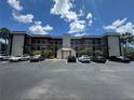Multi-story condo building featuring a well-maintained parking lot and palm trees against a clear blue sky at 1999 Kings Hwy # 26A, Punta Gorda, FL 33980
