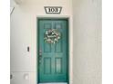 Close-up of a teal front door adorned with a welcome wreath, creating a warm and inviting entrance at 245 Cape Harbour Loop # 103, Bradenton, FL 34212