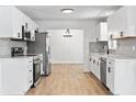 Modern kitchen featuring white cabinets, stainless appliances, stylish hardware, and wood-look floors at 3236 Kingswood Dr, Sarasota, FL 34232