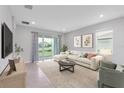 Bright living room with neutral tones, tile floors and sliding glass doors to backyard at 407 157Th E Ct, Bradenton, FL 34212