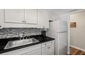 Bright kitchenette with white cabinets, stainless steel sink, and black countertop at 6016 Hibiscus Dr, Bradenton, FL 34207