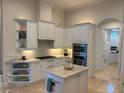 Bright kitchen featuring white cabinets, a center island with a marble countertop, and stainless steel appliances at 624 Mourning Dove Dr, Sarasota, FL 34236