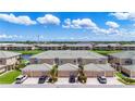 Aerial view of townhomes showcasing a tiled roof, private garages, and the surrounding community pond at 6604 7Th Avenue W Cir, Bradenton, FL 34209