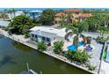 Aerial view of waterfront home with a pool, canal access, and lush tropical landscaping with seating around the pool at 726 Jungle Queen Way, Longboat Key, FL 34228