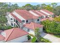 Exterior of a condominium featuring a tile roof, attached garage, and verdant landscaping at 7674 Fairway Woods Dr # 1605, Sarasota, FL 34238