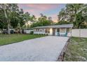 Charming single-story home with a gravel driveway, lush trees, and well-kept lawn at 946 Charlotte Ave, Sarasota, FL 34237