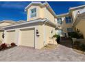 Charming yellow two-story home featuring a brick driveway and a two-car garage at 1251 Burgos Dr # 303, Sarasota, FL 34238