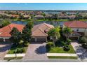 An aerial view showcases lush landscaping, paver driveway, and terracotta roof in a lakefront community at 13026 Ramblewood Trl, Bradenton, FL 34211