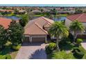 An aerial view captures this home's lush landscaping, three-car garage, and beautiful terracotta roof at 13026 Ramblewood Trl, Bradenton, FL 34211