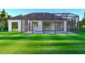 Backyard view featuring a screened-in pool and spacious lawn, perfect for outdoor living at 1573 Greenley Rd, North Port, FL 34286