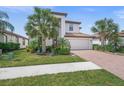 Charming two-story home featuring a brick driveway, attached garage, and well-manicured lawn with mature landscaping at 19369 Nearpoint Dr, Venice, FL 34292