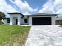 Charming one-story home with a paver driveway, black garage door, clean landscaping, and a stucco exterior at 2692 Pretzel Ln, North Port, FL 34286