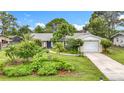 Inviting single-story home features a manicured front yard with lush landscaping, an attached garage, and a quaint walkway to the entry at 408 67Th W Ave, Bradenton, FL 34207