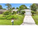 Cozy single-story home boasts a well-maintained lawn and landscaping, plus an attached garage and a welcoming walkway to the entrance at 408 67Th W Ave, Bradenton, FL 34207