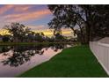 Picturesque lake view with lush green grass, a white fence, and beautiful sunset reflections at 4410 67Th Avenue E Cir, Sarasota, FL 34243