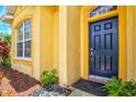 Home's front entrance with a dark blue door, textured siding, and decorative stone landscaping at 5004 Creekside Trl, Sarasota, FL 34243