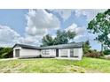 A one-story house featuring an attached garage and a dark roof against a cloudy blue sky at 5009 Jody Ave, North Port, FL 34288