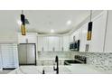 Open-concept kitchen featuring stainless steel appliances, white cabinetry, and stylish pendant lighting at 5009 Jody Ave, North Port, FL 34288