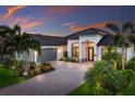 Charming single-Gathering home featuring a paver driveway, tropical landscaping, and stone accents at 5804 Mulligan Way, Lakewood Ranch, FL 34211