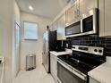 Galley kitchen featuring stainless steel appliances and black backsplash at 6253 Whetstone Ct, Palmetto, FL 34221