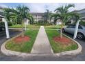 Condo building entrance featuring sidewalk, manicured lawn and mature landscaping with palm trees at 6507 Stone River Rd # 302, Bradenton, FL 34203