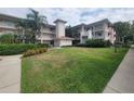 Well-maintained condo building surrounded by a manicured lawn with mature trees and tropical vegetation at 6507 Stone River Rd # 302, Bradenton, FL 34203
