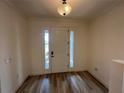 Bright foyer featuring a white door with sidelights, wood-look floors, and a modern light fixture at 931 Signet Dr, Apollo Beach, FL 33572
