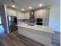 Modern kitchen with white cabinets, stainless steel appliances, and a quartz countertop island at 931 Signet Dr, Apollo Beach, FL 33572