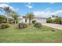 A beautiful home with a three car garage and paver driveway is surrounded by lush landscaping at 103 Graham Se St, Port Charlotte, FL 33952