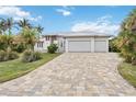 A beautiful home with a three car garage and paver driveway is surrounded by lush landscaping at 103 Graham Se St, Port Charlotte, FL 33952