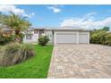 A beautiful home with a three car garage and paver driveway is surrounded by lush landscaping at 103 Graham Se St, Port Charlotte, FL 33952