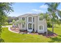Beautiful two-story home featuring a landscaped yard with mature palm trees and a circular driveway at 18307 White Fang Ct, Parrish, FL 34219