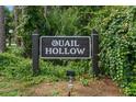 Community sign for Quail Hollow with lush greenery in background at 3003 Quail Holw # 10, Sarasota, FL 34235